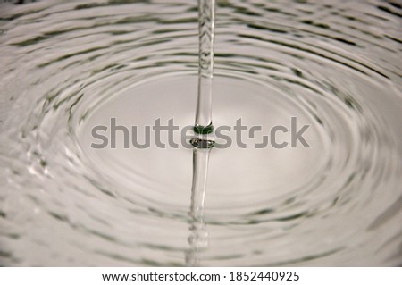 Jet of falling water.  Drops of water on a  glass. Circles on the water.