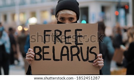 Young woman with face mask holding banner with writtings - free belarus. High quality photo