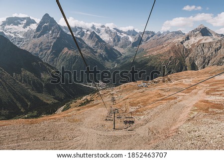 Aerial lift with open chairs in mountain. Cable car at ski resort. Transport in mountain. Vacation and ecotourism in Caucasus mountain.
