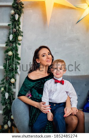 Portrait of a happy mother and a charming child celebrating Christmas. New year holiday. Baby with his mother in a festively decorated room with a Christmas tree and decorations.