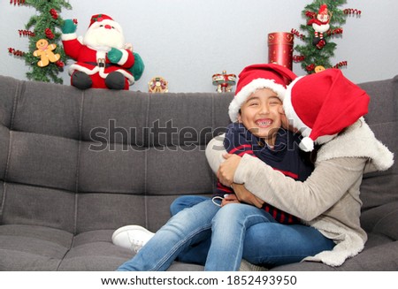 
latin mom and child with protection mask and santa claus hat, christmas decoration, new normal covid-19