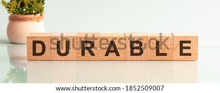 durable word written on wood block. durable motivation text on wooden blocks business concept white background. Front view concepts, flower in the background Royalty-Free Stock Photo #1852509007