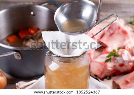 Passing the bone broth through a sieve and through a paper napkin. Concentrated Bone Broth in a Glass Jar
