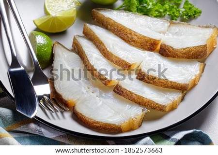 halibut fish slices served with lime on a plate on a marble table, horizontal view from above