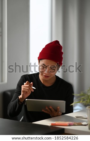 Portrait of graphic designer or photographer is using stylus pen drawing on portable tablet computer.