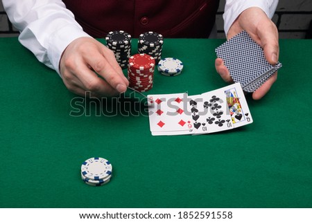 the croupier closes the winning combination on the green cloth of the poker table, close-up view