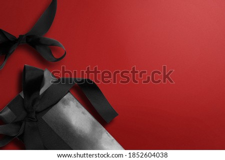 Black gift box with black ribbon on colored background. Black Friday concept