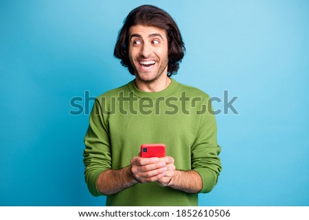 Portrait of astonished handsome person look empty space green sweater isolated on blue color background
