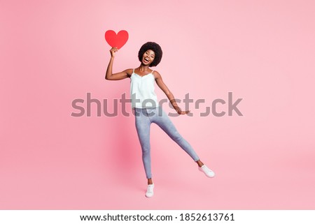 Full length photo of attractive curly hairdo person hand hold heart symbol sneakers isolated on pink color background