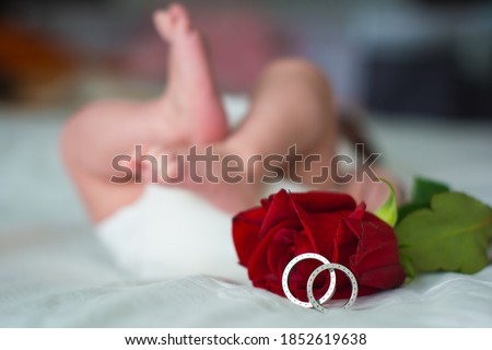 Feet of a newborn and his parents wedding rings. Legs of a newborn baby with mom and dad's wedding ring. Happy Family concept. Royalty-Free Stock Photo #1852619638