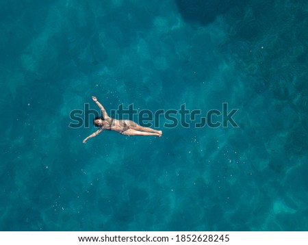 Aerial picture of the girl laying on the sea surface.