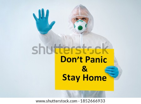 Healthcare worker showing stop gesture, holds paper with text "Don't panic & Stay home"