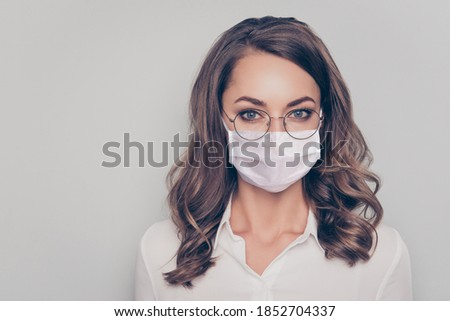 Photo portrait of cute girl in glasses wearing white face mask isolated on grey colored background