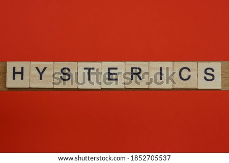 word hysterics from small gray wooden letters lies on a red background