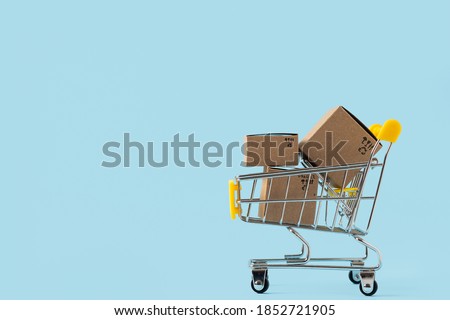 Toy shopping cart with boxes on blue background. Copy space for text or design. Sale, discount, shopping and delivery concept. Consumer society trend Royalty-Free Stock Photo #1852721905