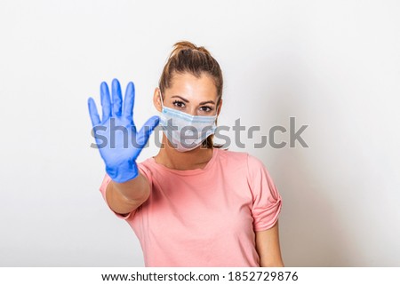 Portrait of young woman wearing face protective mask to prevent Coronavirus and anti-smog. Portrait of young woman wearing face mask showing stop sign with her hand. Covid-19 prevention concept