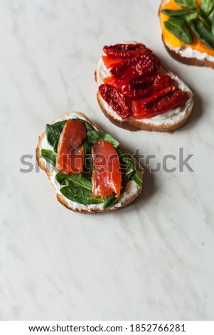 Assorted bruschetta or tapas set with different savory with cream curd cheese. sandwich with dried tomato with fresh yellow tomatoes, green spinach and free-fried red fish. healthy snack and breakfast