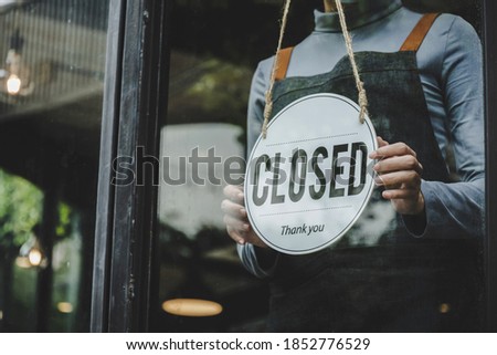 Closed. friendly waitress wearing protection face mask turning open sign board on glass door in modern cafe coffee shop, cafe restaurant, retail store, small business owner, food and drink concept