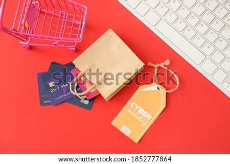 Shopping bag with credit cards, trolley, computer keyboard and tag with text CYBER MONDAY on color background