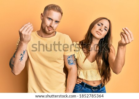 Young couple of girlfriend and boyfriend hugging and standing together doing italian gesture with hand and fingers confident expression 