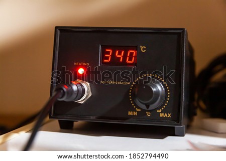 Simple soldering station box turned on, heated to 340 degrees celsius, front panel digital display visible. Heating soldering equipment, electrician's work tools concept Royalty-Free Stock Photo #1852794490