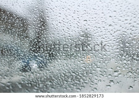 very poor view of the road, through a dirty windshield covered with ice, snow and water, against a blurred foreground and background with bokeh effect