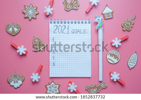 Holiday decorations and notebook with 2021 goals, plans, dreams. New Year and Christmas concept. Flat lay. Top view.