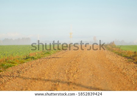 An old country asphalt road through the village in a fog. Street sign close-up. Clear blue sky. Rural scene. Transportation, countryside, road trip, driving. Symbol, copy space, graphic resources