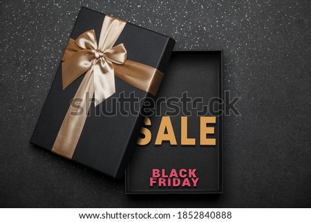 Open black gift box with golden bow and lettering inside, black friday sale. Ready-made banner design. Black granite background