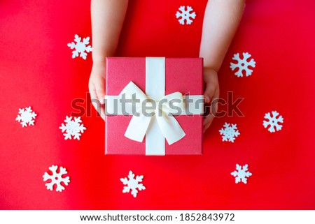 Christmas red background with Christmas tree, children's hands. Top view