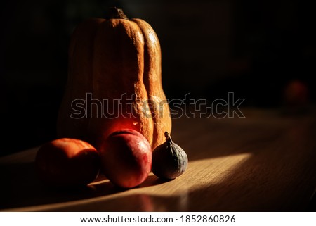 Seasonal fruits on a dark background lying on a wooden table in a beam of light, blurred background. Photo in dark colors