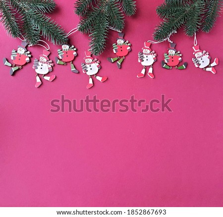 Pattern of wooden Christmas tree decorations on a pink paper background. Christmas snowman. Place of text