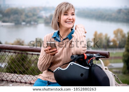 Pretty Blonde Young Woman using Smartphone outdoors in the City Viewpoint by the river. Taking a break for checking her invoices and social networks