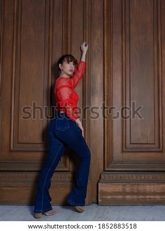 beautiful young woman with curly hair and red shirt at church door