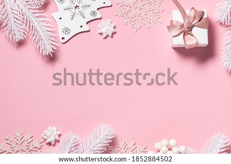 Beautiful festive Christmas and New Year frame made with toys, fir tree branches, white decorations on pink pastel background. Copy space for your text. Christmas greeting card concept.