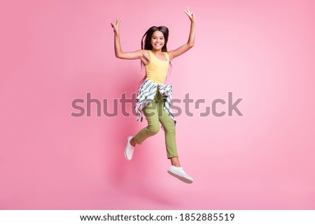 Full length photo of school girl wear casual outfit jumping showing v-sign isolated pastel pink color background