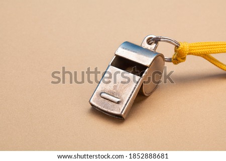 Vintage silver whistle on soft brown paper background. Referee trainer sport competition sound instrument. 