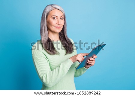 Photo of charming clever old lady hold tablet point finger into screen isolated over blue pastel color background