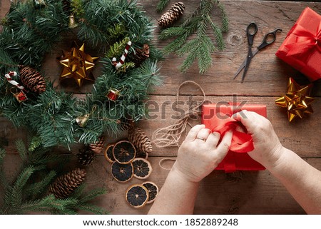 Christmas wreath on wooden background. Grandma hands.