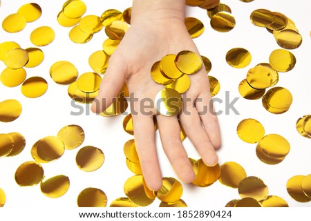 Hand holding golden, festive, paper confetti in the form of circles isolated on white background. Background with golden confetti. Saving money concept