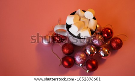 Trendy Christmas background of of hot chocolate with marshmallow, decorated with balls on pink - top view