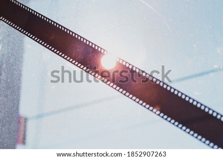 Blank old 35mm photographic filmstrip reel on a window with the sun behind