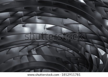 Concentrically positioned silver-colored curved metal plates and intersecting cross members create a futuristic abstract composition. Textured abstract background. Selective focus. Close-up.
