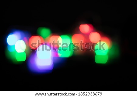 Multiple multi coloured green, purple and red out of focus spots of light fairy lights on black background. Colour, Christmas and celebration concept.