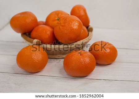 Mandarins in a basket on a white wooden background. Selective focus. Minimalist concept for your mockup and project.
