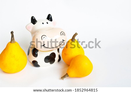 Three decorative orange pumpkins and a white and black cow figurine on a white background. Healthy vegetables, vitamins and trace elements. Hello autumn. Autumn harvest. Farm