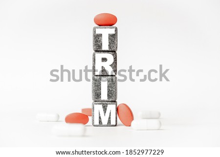 a group of white and red pills and cubes with the word trim on them, white background. Concept carehealth, treatment, therapy.