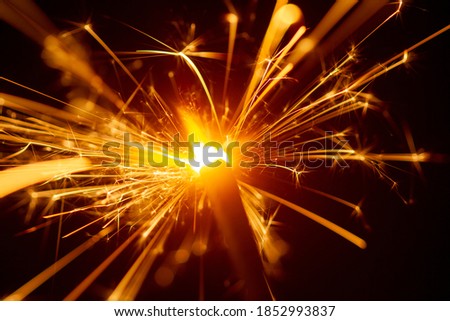 Sparks and fire on a black and blue background. Festive Merry Christmas sparklers. Golden Magic lights for holiday poster, birthday or party concept.