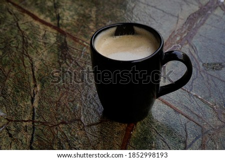 Black coffee cup with coffee on wooden colorful background