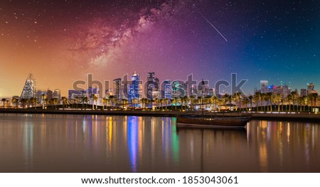 Doha Qatar skyline at night showing skyscrapers  lights reflected in the Arabic gulf and dhow in foreground with stars in sky in background Royalty-Free Stock Photo #1853043061